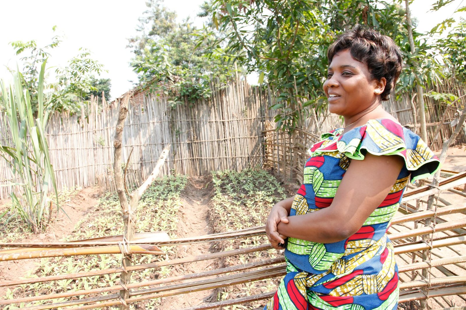 A confident community leader smiling beside a cultivated garden plot